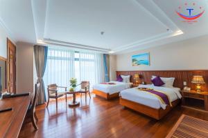 归仁Vietnam Taste Hotel Quy Nhon - Beachfront的酒店客房设有两张床和一张桌子。
