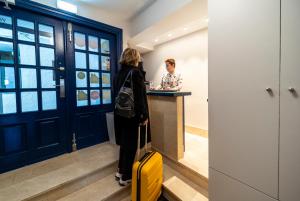 蒙达卡Hotel&Spa El Puerto的站在柜台的一位妇女,手提箱是黄色的