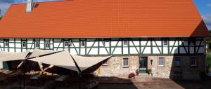 FrohburgFewo - a70760的一座带橙色屋顶、桌子和遮阳伞的大型建筑