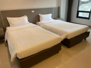 Sinsiri hostel的两张睡床彼此相邻,位于一个房间里