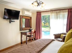 博克斯堡Sunward Park Guest House & Conference Center的酒店客房配有一张床、一张书桌和一台电视。