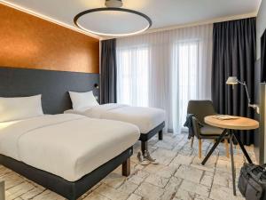 班贝格ibis Styles Bamberg的酒店客房设有两张床和一张桌子。