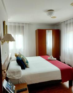阿拉萨特-蒙德拉贡Pension Uxarte的卧室配有一张大白色床和红色毯子