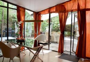 奥佩德LASUITE Domaine Bertuli, heated Pool, Aircon的用餐室配有橙色窗帘和玻璃桌椅