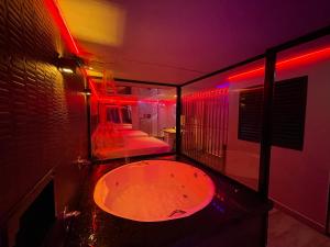 圣保罗Adrenalina Motel Itaquera - Arena Corinthians的红色灯的房间里设有一个大浴缸