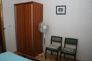 苏提万Double Room Sutivan 2943b的一间卧室配有两把椅子、一个风扇和一个衣柜