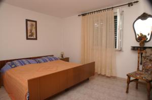 苏佩塔尔Apartments with a parking space Supetar, Brac - 2850的卧室配有床、椅子和窗户。