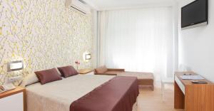 甘迪亚RH里维埃拉酒店 - 仅限成人 的一间卧室配有一张床、一张书桌和一台电视。