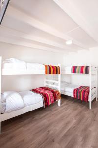 圣佩德罗·德·阿塔卡马Hostal Copart的铺有木地板的客房内配有两张白色双层床。