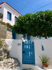 斯基亚索斯镇Oikies Skiathos的白色建筑中一扇蓝门,有树