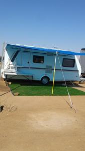 埃拉特קרוואן על החוף的停在田野里的蓝色和白色大篷车