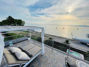 巴多利诺Bardolino Luxury的阳台配有沙发,享有水景