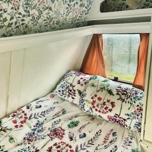 基尔肯尼Cosy Caravan at Carrigeen Glamping的小房间一张床位,配有花卉壁纸