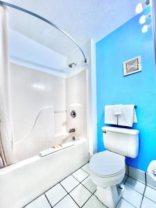 Bayou La BatreBayou Inn & Suites的浴室设有蓝色的墙壁、卫生间和浴缸。
