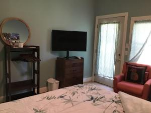 罗克波特Adorable Garden Suite的一间卧室配有一张床、一台电视和一把椅子