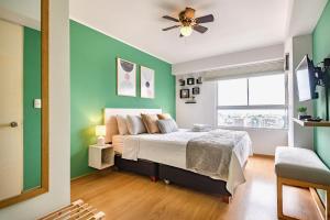 利马ALU Apartments - Limit with Miraflores Panoramic City View的一间带绿色墙壁的卧室和一张带吊扇的床
