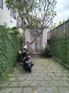 沙努尔Ngetis Home Stay的停在围栏旁的石头路上的摩托车