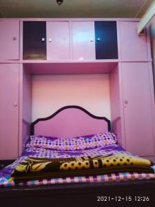 亚历山大Nice house的粉红色客房的一张床位,配有紫色床头板