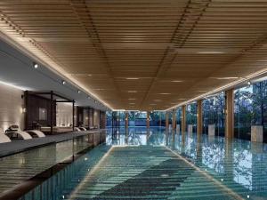 杭州杭州良渚洲际酒店的一座带玻璃窗的建筑中的游泳池