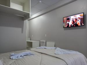 CaçadorSognare Hotel的卧室配有一张壁挂式平面电视的床。