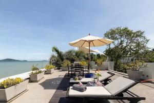 拉威海滩拉亚海滨度假屋的一个带椅子和遮阳伞的庭院和水