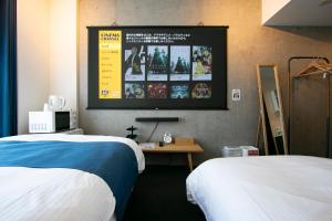 东京Theatel Haneda Ⅱ的客房设有两张床和一台墙上的电视。