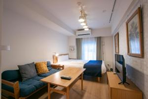 东京KARIO SASAZUKA TERRACE的酒店客房配有床、沙发和桌子。