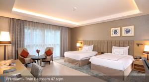 迪拜Grand Cosmopolitan Hotel的酒店客房配有两张床和一张书桌