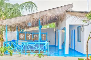 帕杰Beach House Paje的海滩上一座蓝色的建筑,拥有茅草屋顶