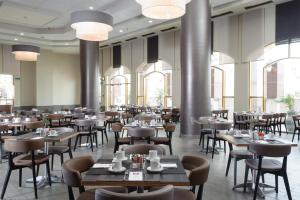 贝尔谢巴内盖夫莱昂纳多酒店的用餐室设有桌椅和窗户。