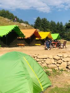 KheergangaCity Escape Camps and Cafe Kheerganga的绿帐篷,人们坐在桌子上