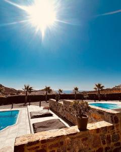 卡拉法蒂斯Aurora Mykonos Villas的享有两个游泳池的景色,阳光在天空中