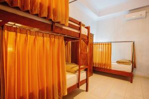 珀尼达岛Kamasanti Hostel的配有橙色窗帘的客房内的两张双层床
