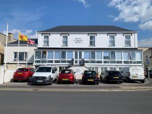 伯翰姆昂斯The Royal Clarence Hotel (on the Seafront)的一座白色的大建筑,前面有汽车停放