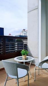吉隆坡Mont Kiara, Arcoris W chilled balcony and TV Box, BeachHolidayHome的阳台配有桌子和两把椅子,设有窗户。