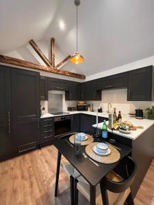 灵伍德Springfield Lodge - Adorable New Forest 1-bedroom guest house的厨房配有黑色橱柜和桌椅