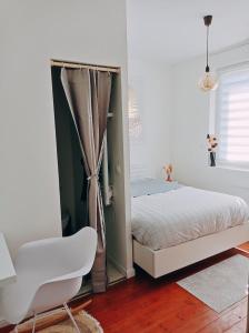 亚眠Irziana - Au jardin d'Henriville的一间卧室配有一张床和一张白色椅子