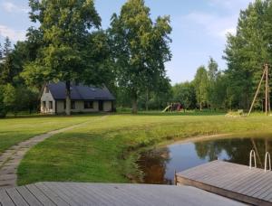 ValtinaVäike-Puusmetsa puhkemaja的公园内的房子,带池塘和游乐场