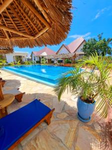 南威Mimi na wewe villa的一个带蓝桌和棕榈树的度假游泳池