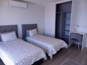 阿科达卡列塔Apartamento Domingos的客房设有两张床、一张桌子和一把椅子。