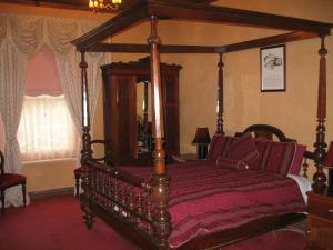 Mintaro敏塔罗公寓的一间卧室配有一张带红色床单的木制天蓬床