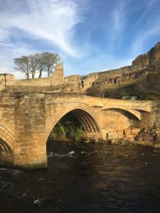 巴纳德城堡Grade II listed house with river and castle views - Barnard Castle的一座石头桥,在河上,山底下