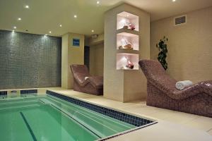 伦敦Montcalm Marble Arch的游泳池位于带椅子和游泳池的房间