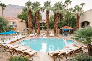 棕榈泉L3 Oasis Hotel的一座游泳池,里面摆放着椅子和棕榈树