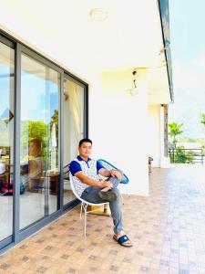 枚州县枚州日落精品酒店的坐在房子外椅子上的男人