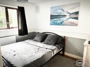Enfield LockEnfield House - Beautiful 2 Bed - Good Transport Free Parking的卧室内的一张床铺,墙上挂着一幅画