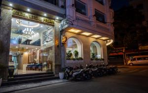 河内Golden Legend Palace Hotel的一群摩托车在晚上停在大楼外