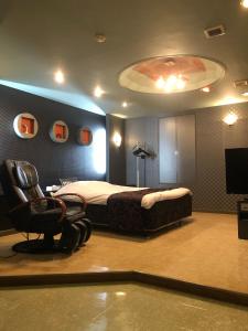 Ginanホテルハンズ的一间卧室配有一张床、一把椅子和电视
