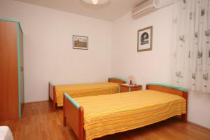 泰斯Studio Nemira 4652c的配有白色墙壁和木地板的客房内的两张床