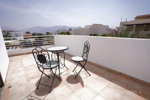 埃拉特YalaRent Afarsemon Apartments with pool - For Families & Couples的阳台上的一张椅子和一张桌子